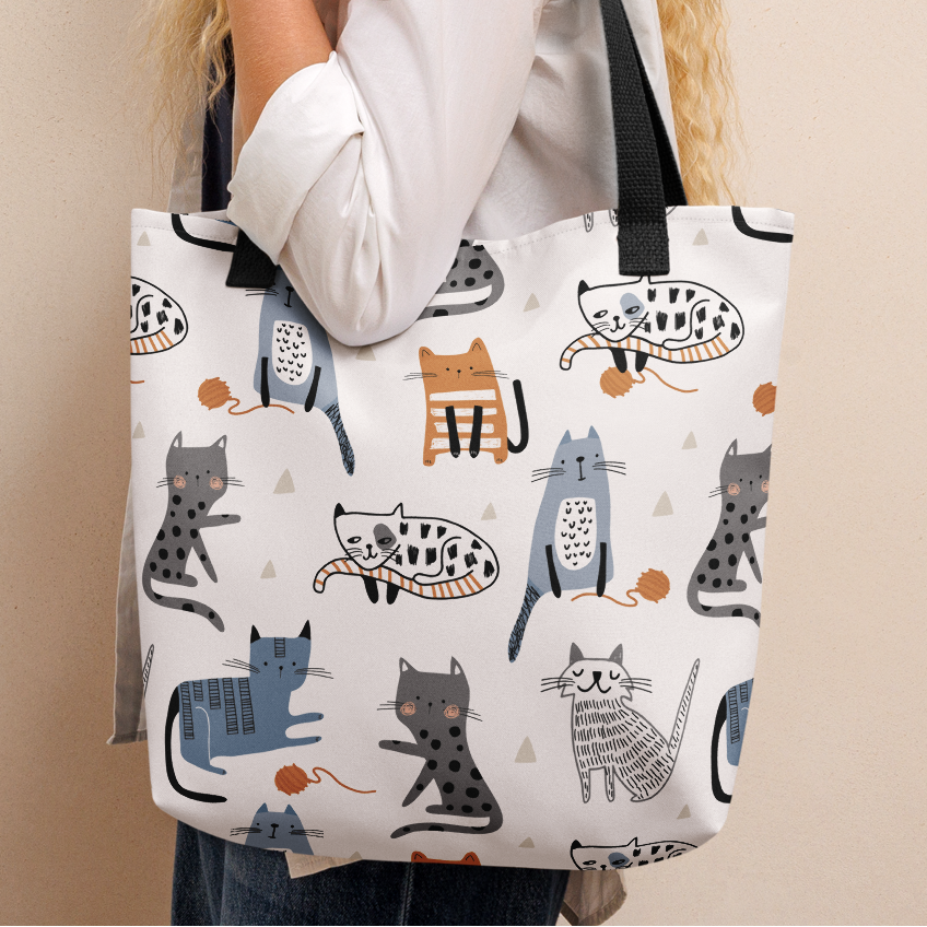 Woman holding a tote bag with cat pattern.