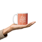 A hand holding a white ceramic mug with orange vertical stripes and the text 'Life is short, buy the pony' in orange and white lettering.